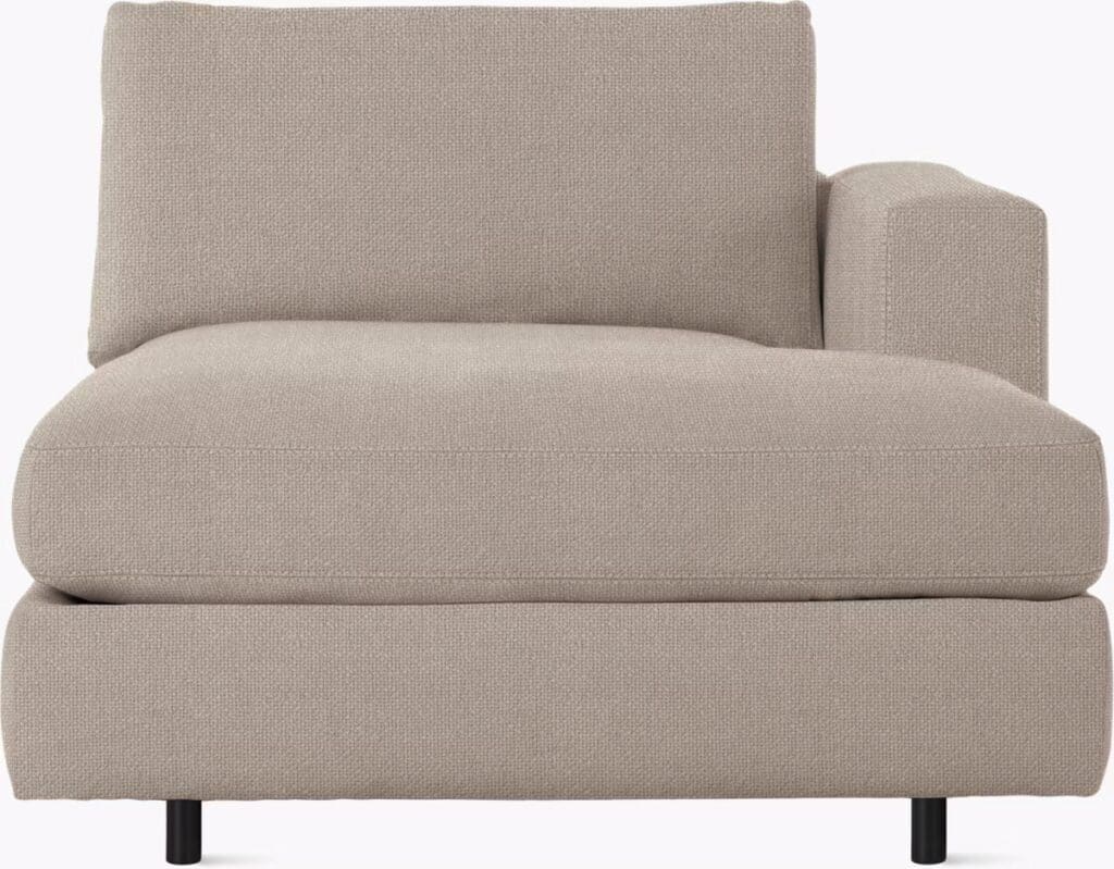 A close-up view of a beige chaise sectional sofa with a minimalistic design and black legs, featuring a plush seat and backrest.