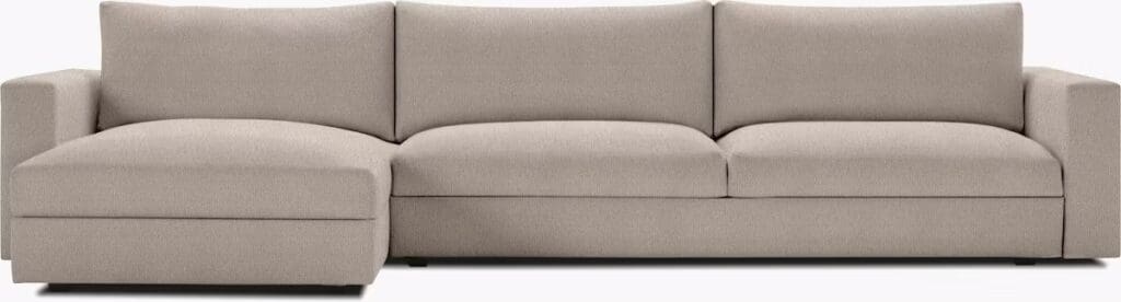 A modern beige sectional sofa with a chaise lounge, featuring plush cushions and a minimalist design.