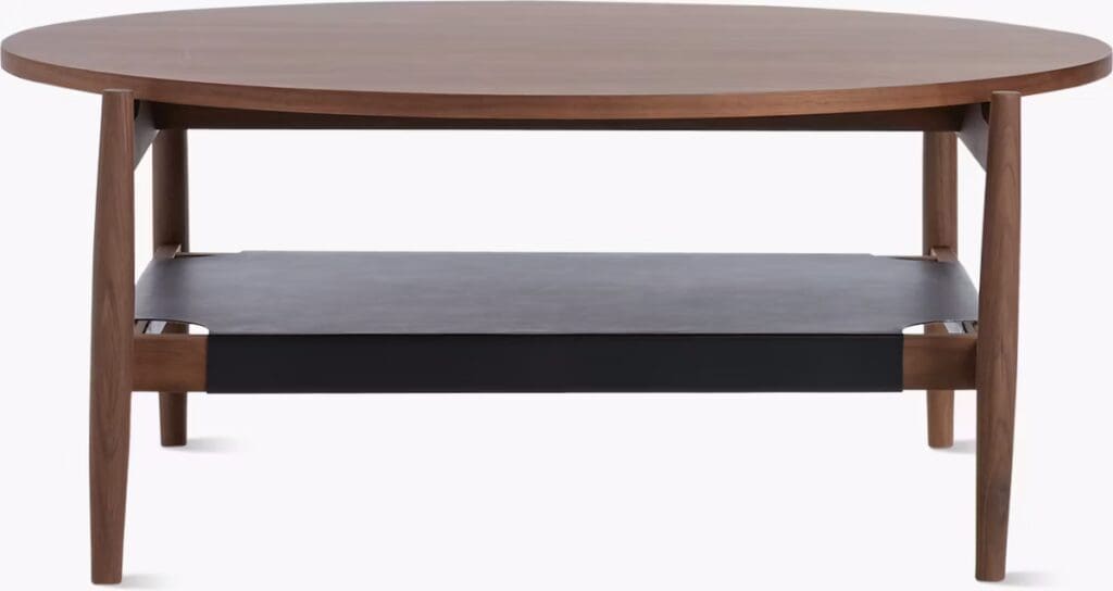 A modern round coffee table with a wooden top and a lower shelf, featuring sleek wooden legs.