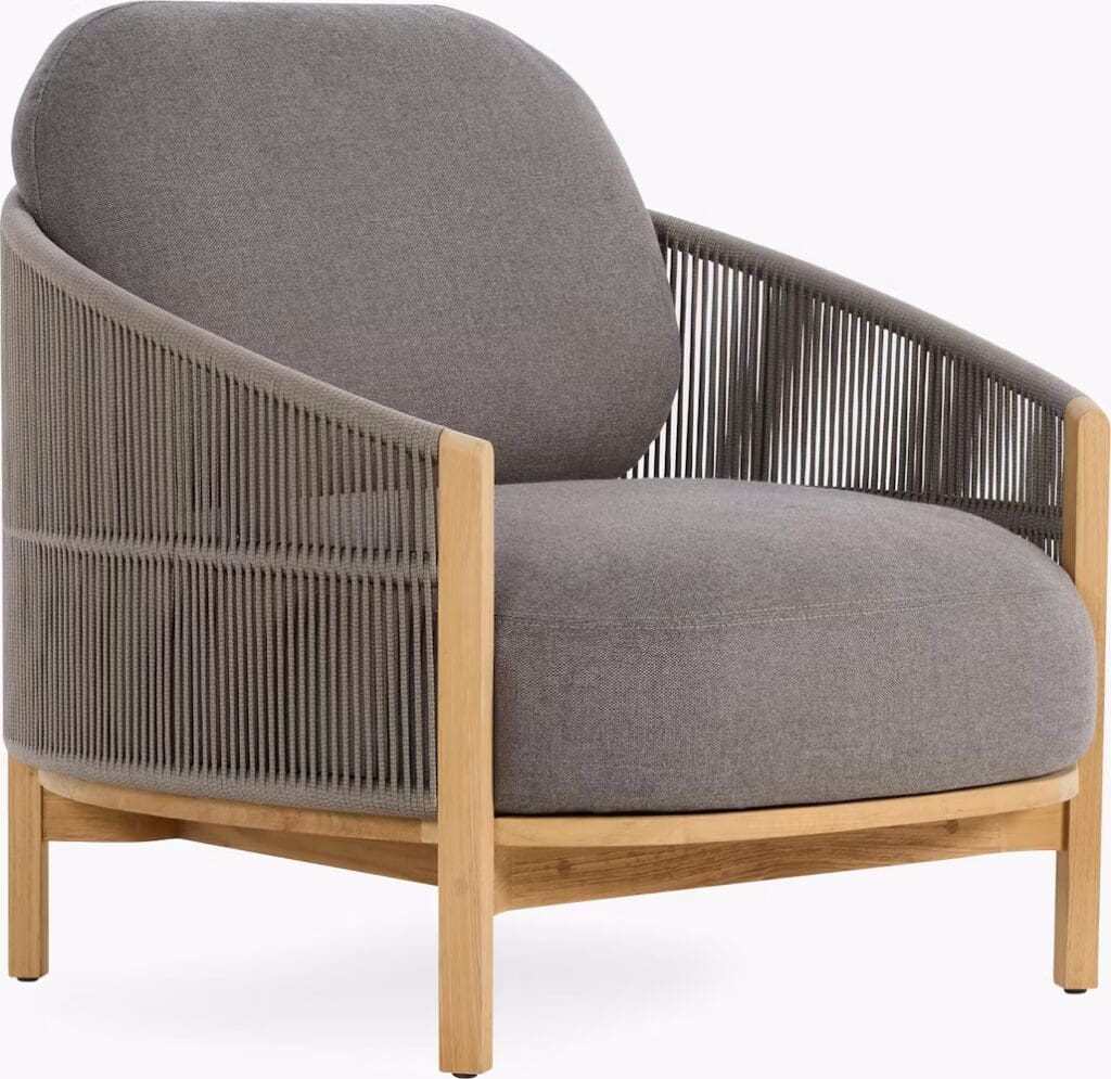 A modern gray armchair with a rounded back and wooden frame, featuring a cozy seat cushion and distinctive woven side panels.