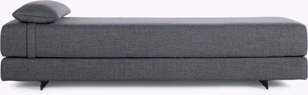 A contemporary gray daybed with a sleek design, featuring a single cushion and a supportive back pillow, showcasing minimalistic style.