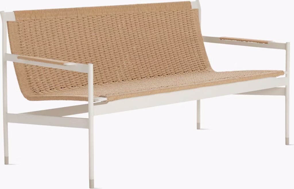 A modern outdoor bench featuring a woven wicker seat with white metal frame and armrests.