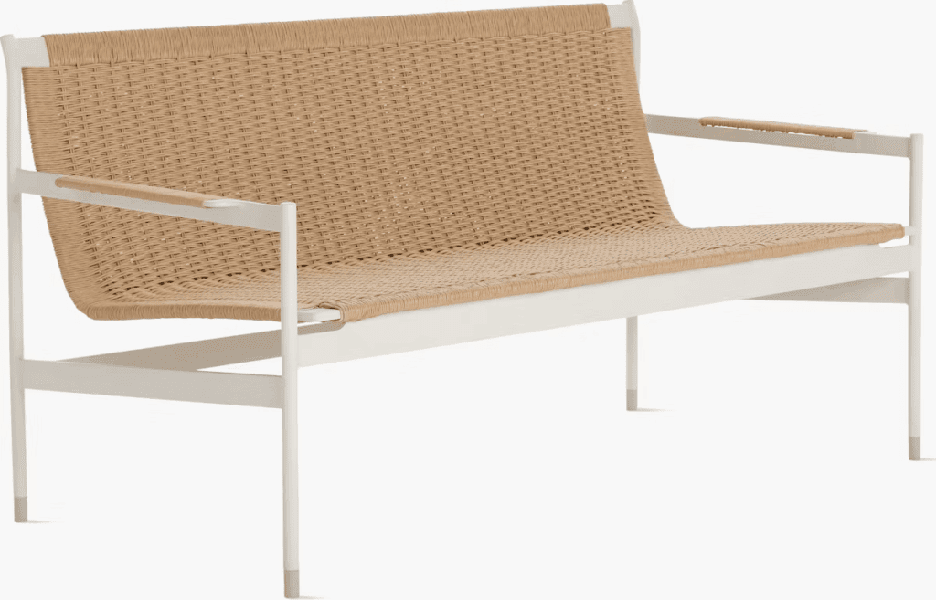 A stylish outdoor sofa with a woven rattan back and seat, featuring a minimalist white frame.