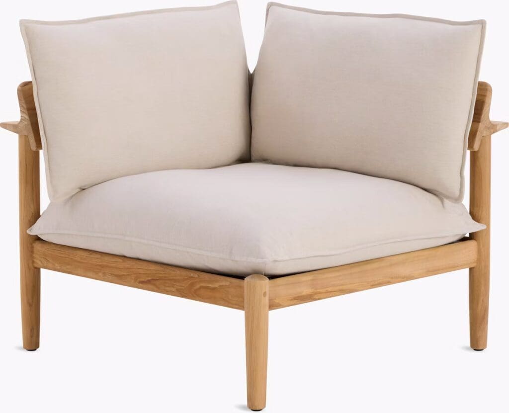 A modern upholstered corner chair with a wooden frame and plush cushions in a neutral color.