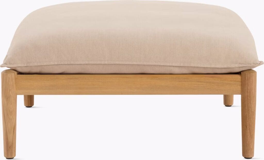 A beige cushion resting on a wooden frame with rounded legs, designed as a modern ottoman.