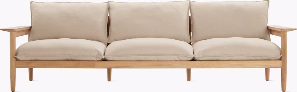 A contemporary three-seat sofa with a wooden frame, featuring plush beige cushions and armrests.