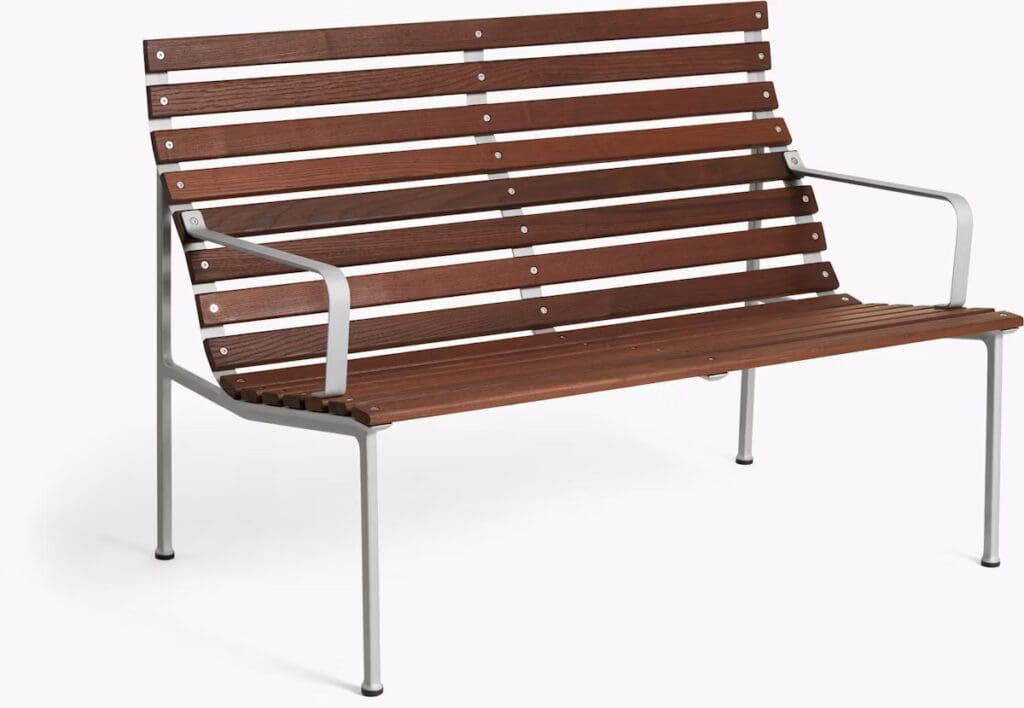 A modern outdoor bench made of slatted brown wood with a sleek metal frame, featuring armrests and a minimalist design.