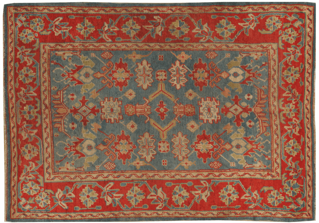 Antique Turkish Oushak rug featuring intricate floral and geometric patterns in red, blue, and cream tones.