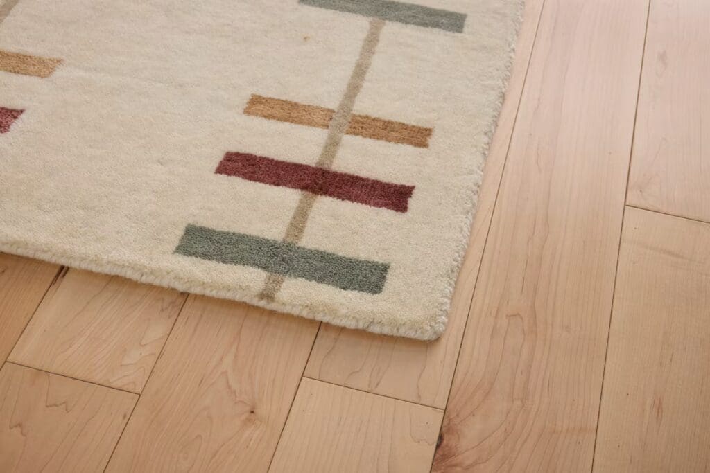 Close-up of a rug with geometric patterns in various colors on a light wooden floor.