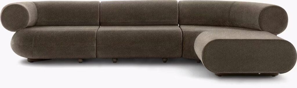 A modern sectional sofa with a rounded design, covered in textured brown fabric, showcasing its unique shape and seams.