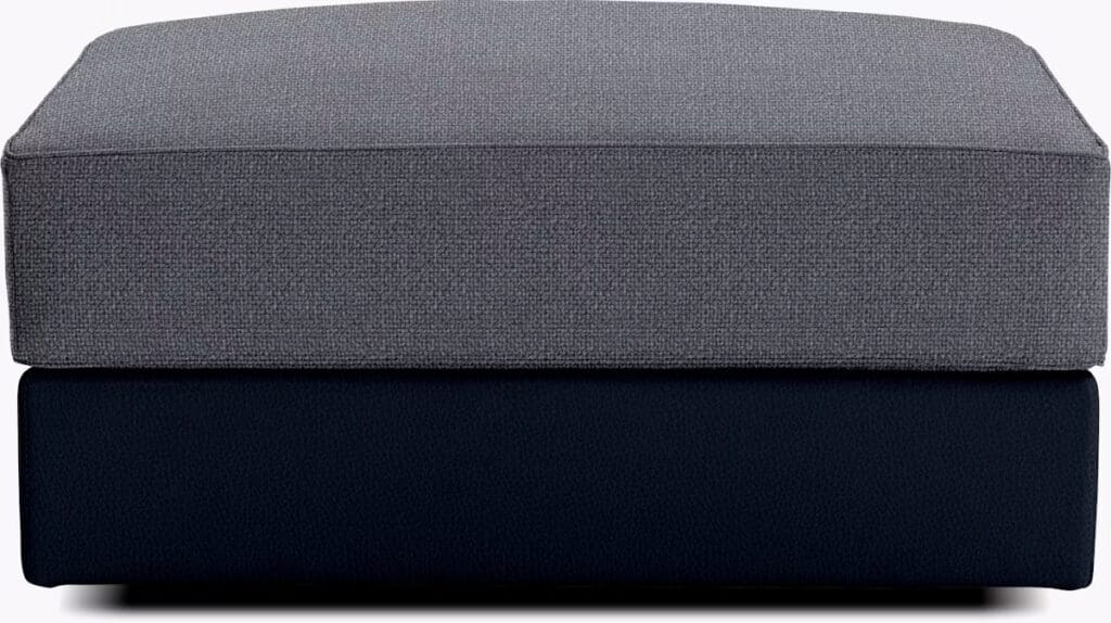 Gray and navy upholstered ottoman with a square shape and two layers, featuring a textured top and a smooth bottom.