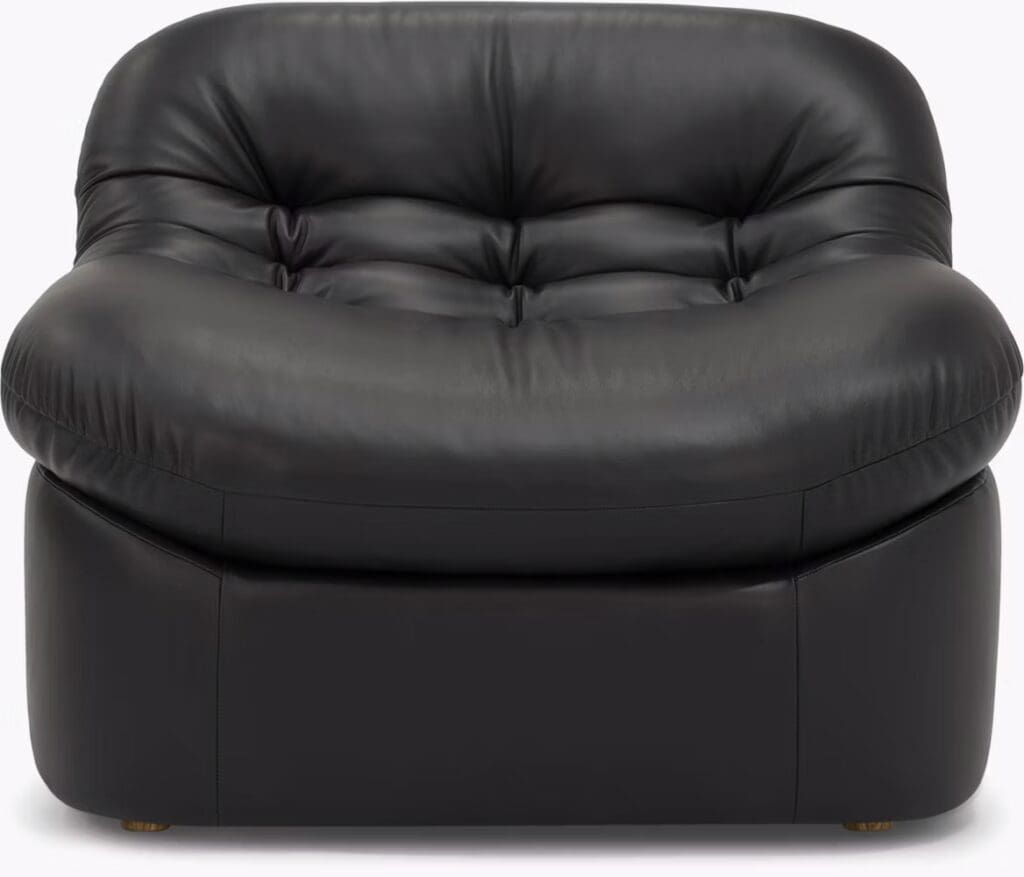 Black leather sofa with a plush, rounded design and tufted cushions.