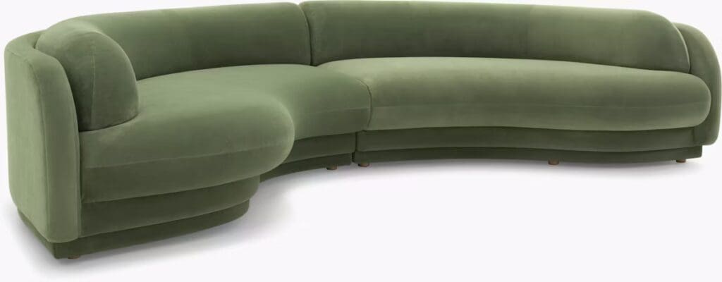 Curved modern green velvet sofa with a smooth, plush design, featuring rounded arms and a low profile.
