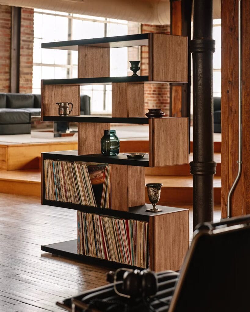 Modern wooden bookshelf with vinyl records and decorative items, set in an industrial-style living space.