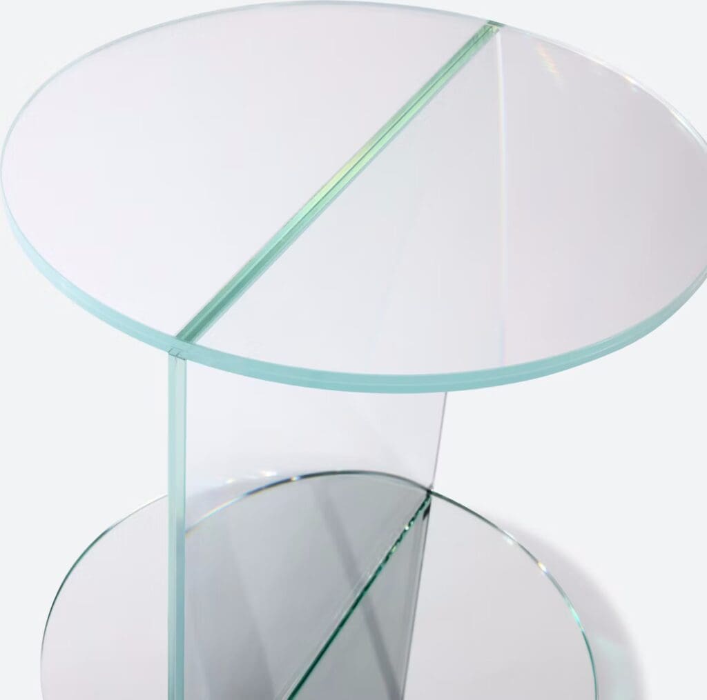 Close-up view of a modern glass side table featuring a round top and a sleek design, showcasing its transparent structure.