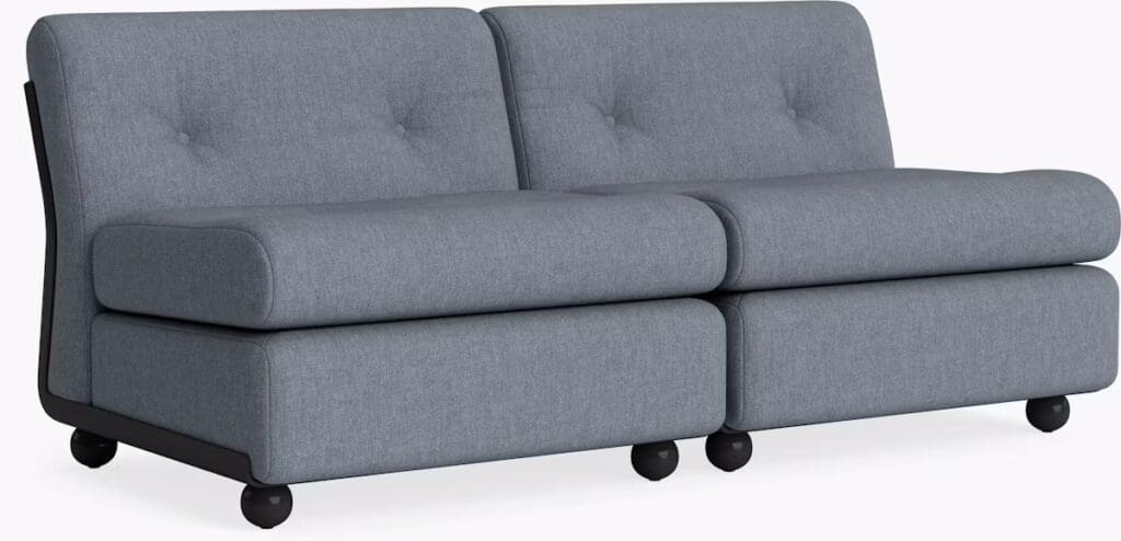 Modern two-seater sofa in gray upholstery with button-tufted backrests and rounded wooden legs.