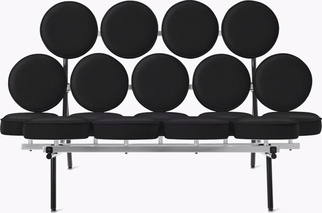 A modern black sofa with circular cushions arranged on a sleek metal frame, showcasing a unique and artistic design.