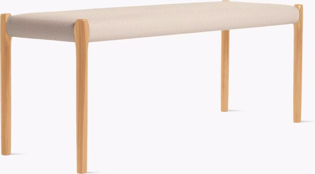 Minimalist bench with a soft cream-colored cushion and light wooden legs.