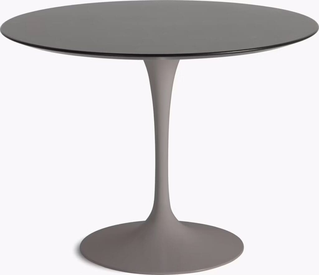 Round modern dining table with a sleek gray surface and a curved pedestal base.