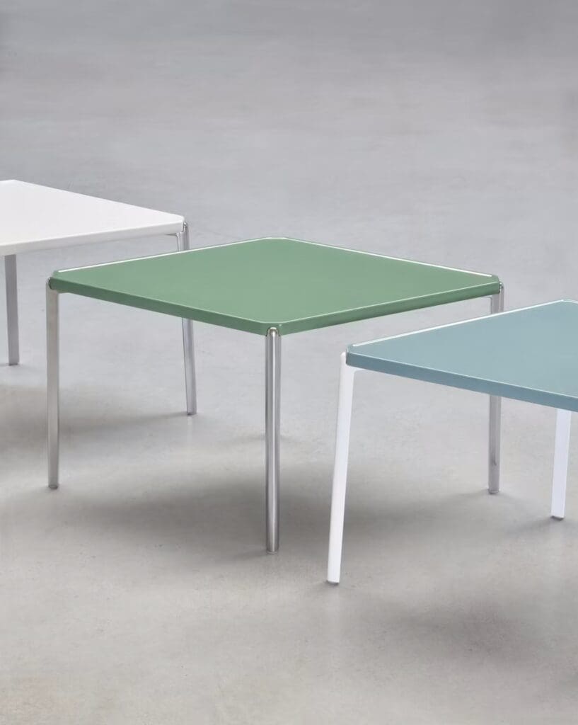 Three modern square side tables in white, green, and light blue, with sleek metal legs against a gray background.