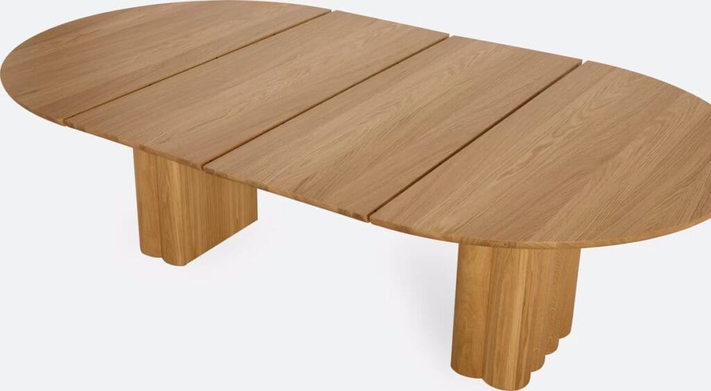 Wooden oval coffee table with three planks and cylindrical legs.